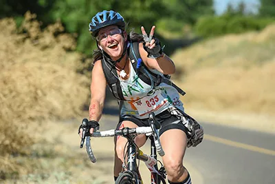 A cyclist on the bike leg flashing a peace sign